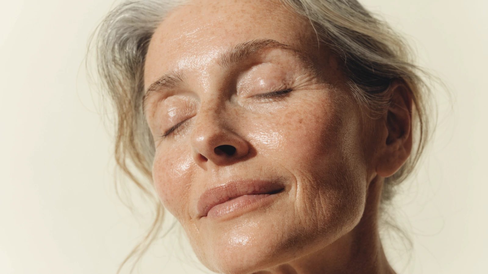 A woman in her late fifties, bare face, natural skin texture with visible fine lines.