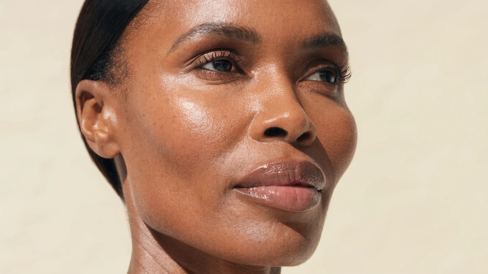 A woman in her forties with deep brown skin, jawline and cheekbone in soft shadow.
