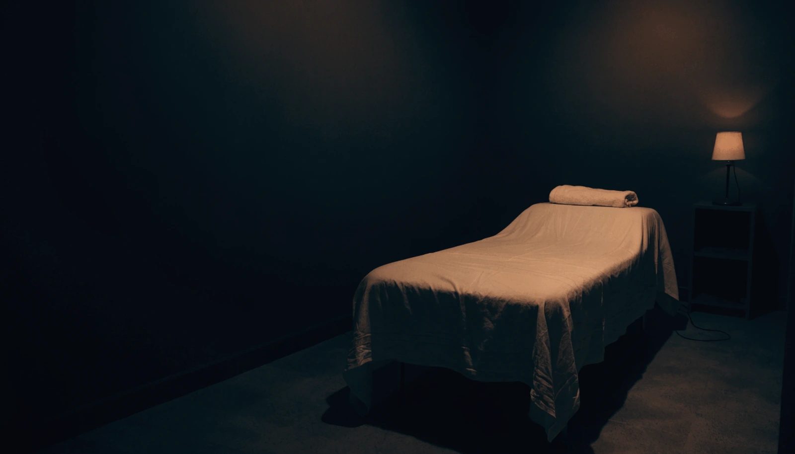 An empty professional treatment room at the end of the day, couch made up in ivory linen.