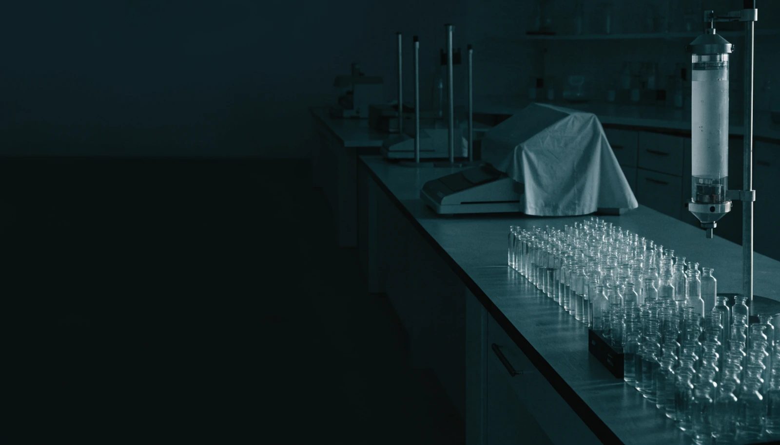 A quiet analytical research laboratory at night, racks of glass vials along a dim bench.